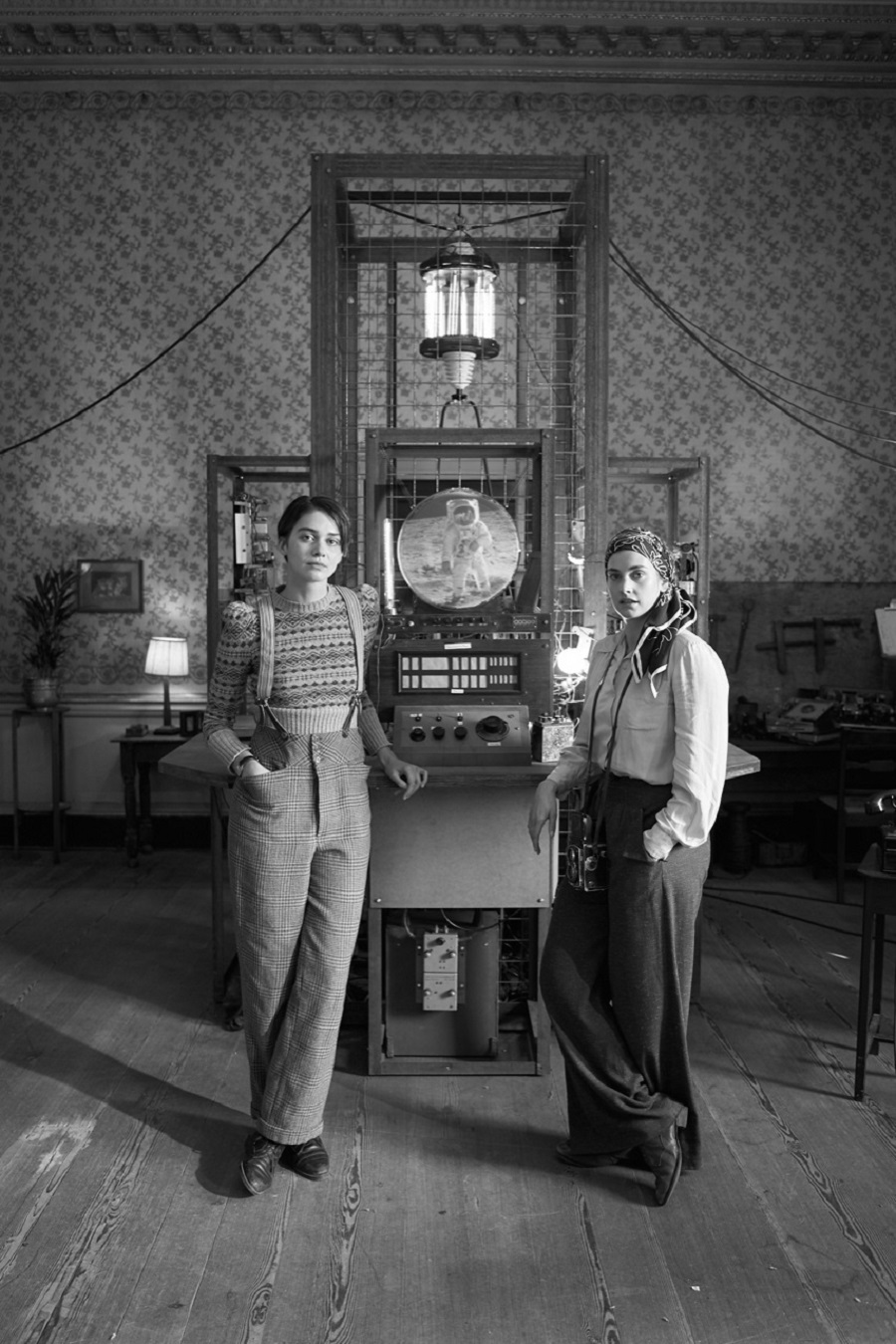 a black and white still from LOLA featuring two women standing in front of a fantastic machine