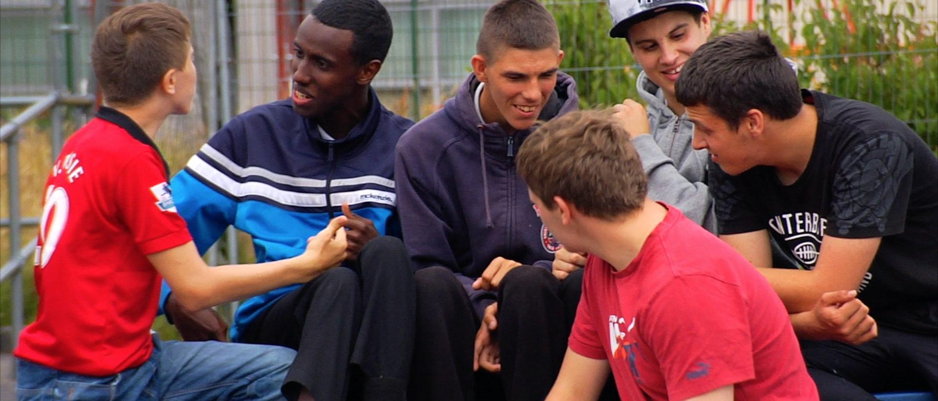 a group of young people sitting outside talking and laughing