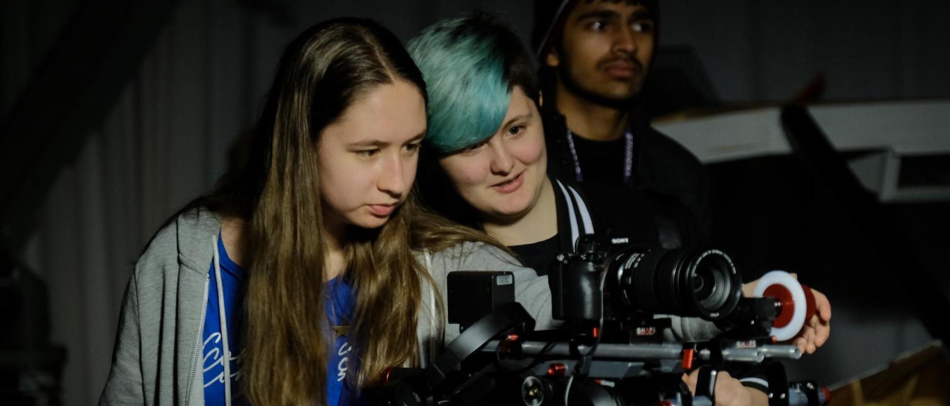 three people working behind a film camera