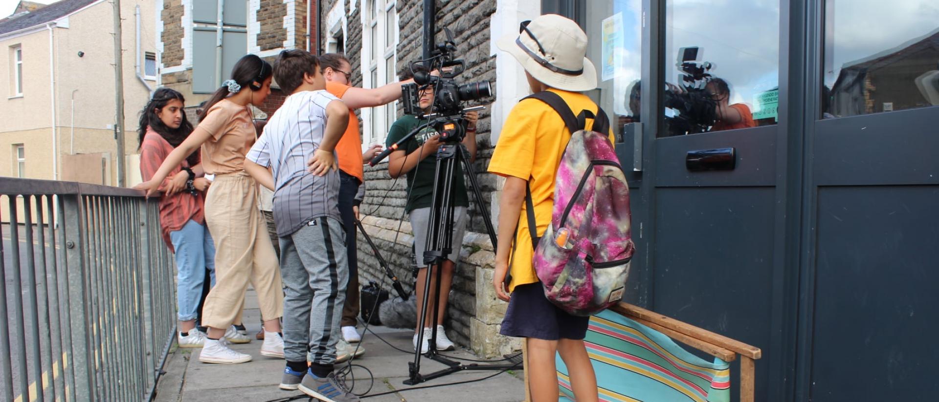 a group of young people outside a building making a film