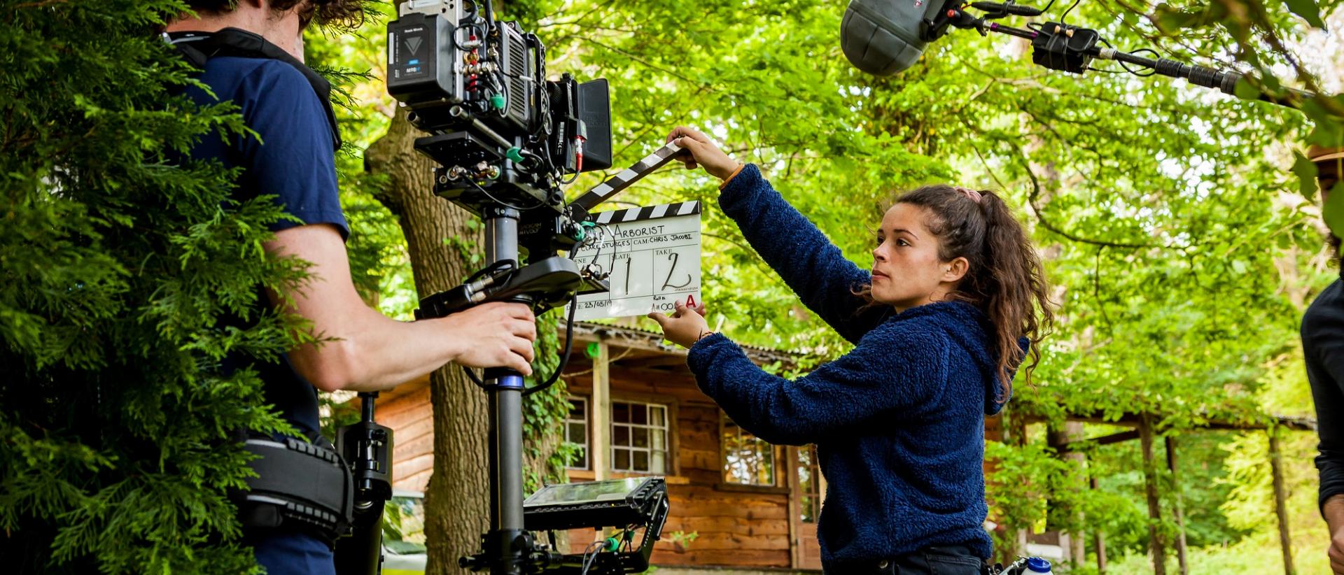 a film crew shooting a film outside a wooden cabin in a forest