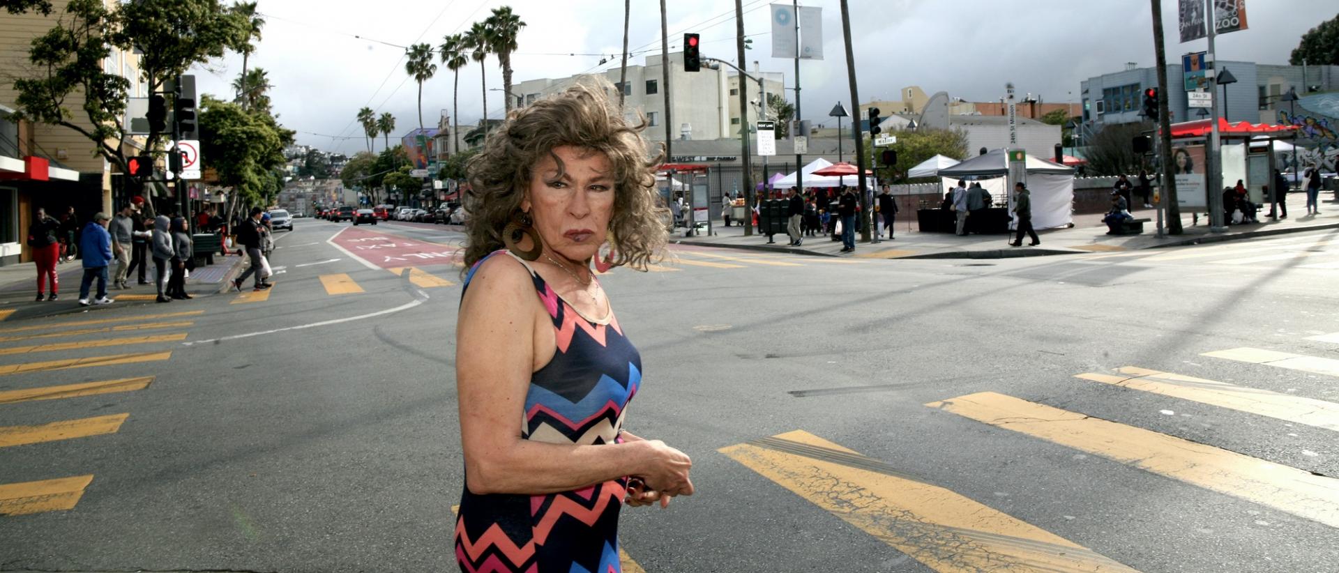 a photo of a person wearing a dress and standing at a road intersection in an american town