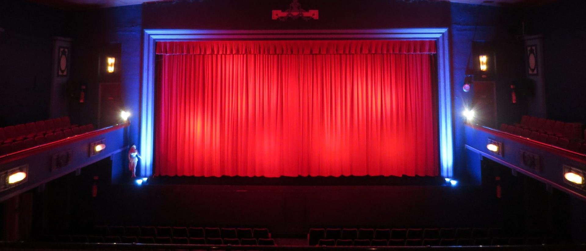 interior of an empty cinema with a red curtain over the screen