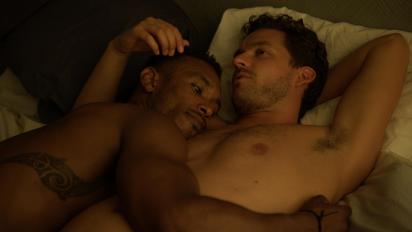 two men hug in bed