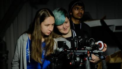 three people working behind a film camera
