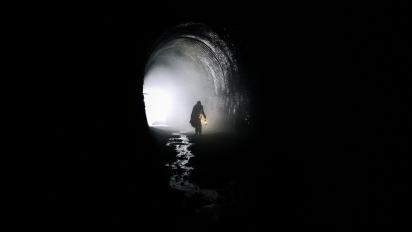 still from jackdaw featuring a person walking through a dark tunnel