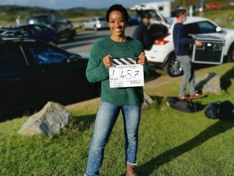 photo of krystal s lowe on the set of her film daughters of the sea, standing outside holding a clapperboard