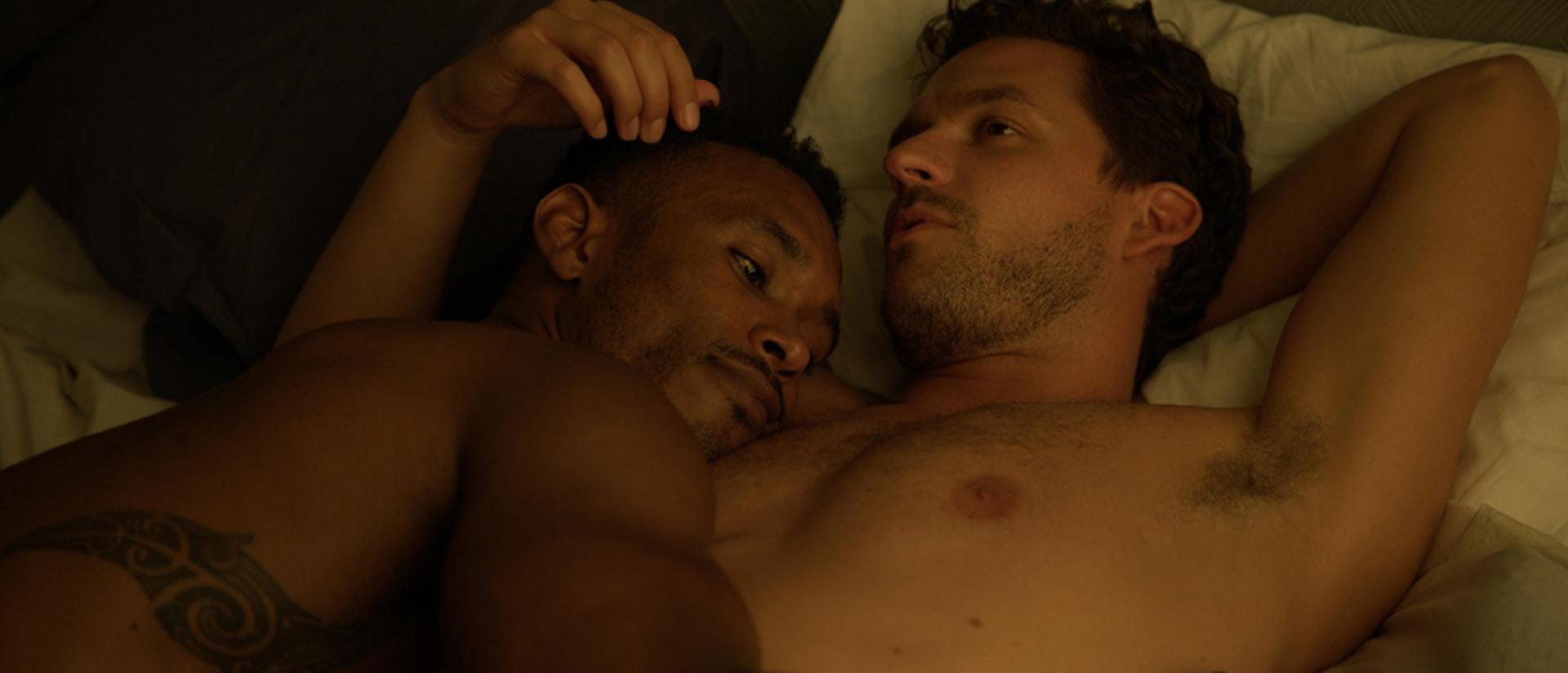 two men hug in bed