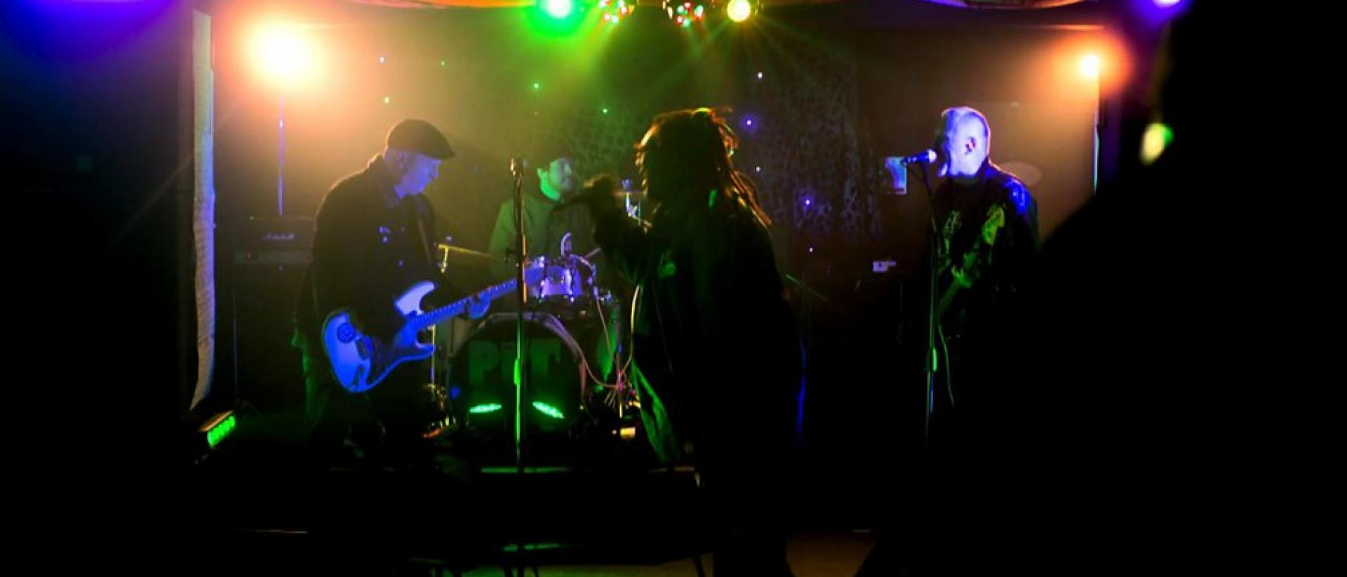 Still from King of the Pit featuring a four-piece rock band playing a gig.