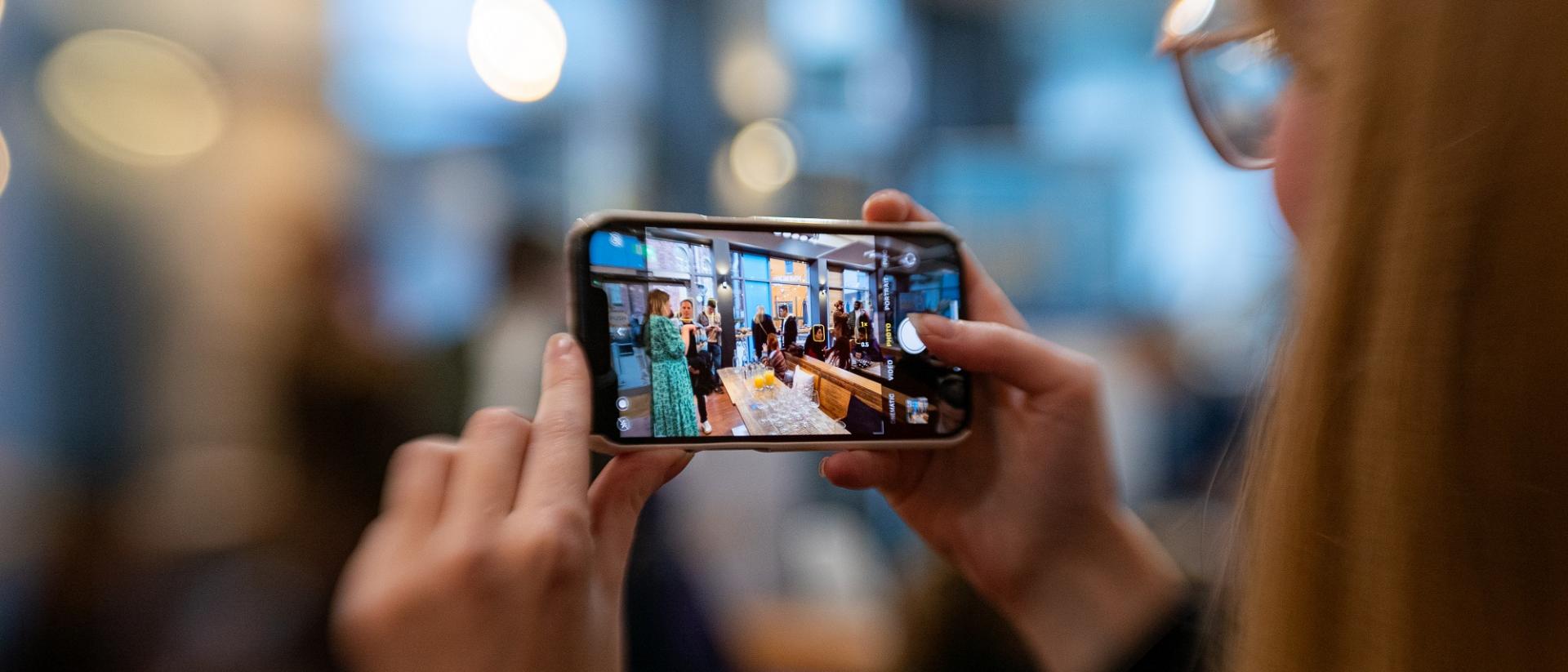 photo of a person filming an event on their phone