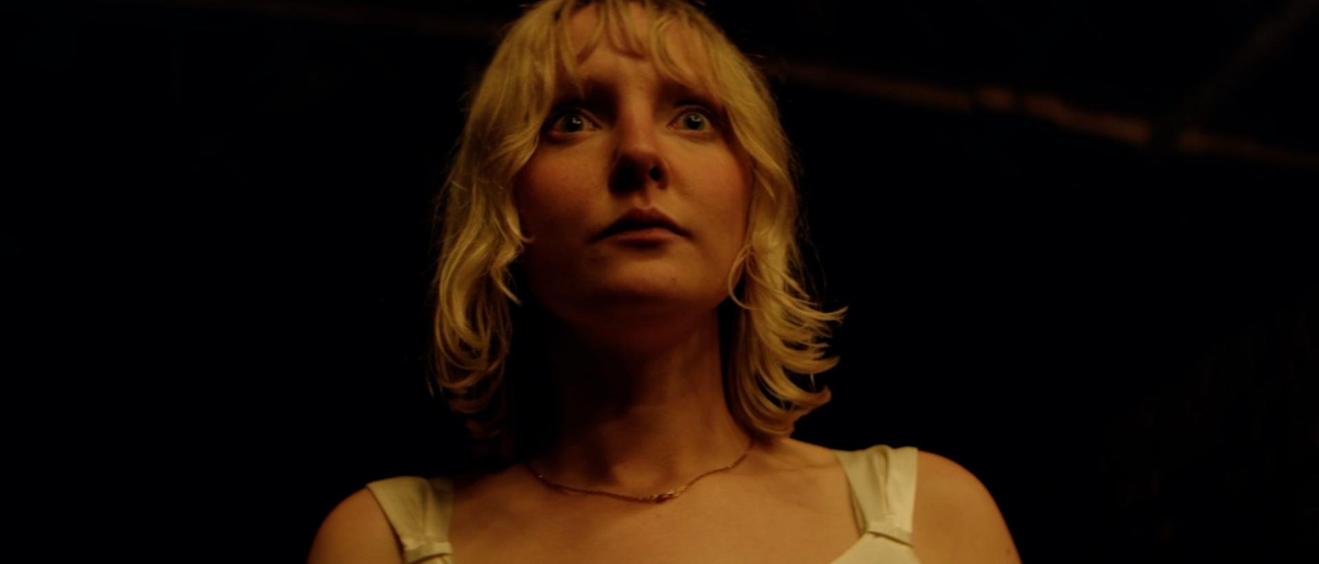 a woman standing in a dark room looking scared