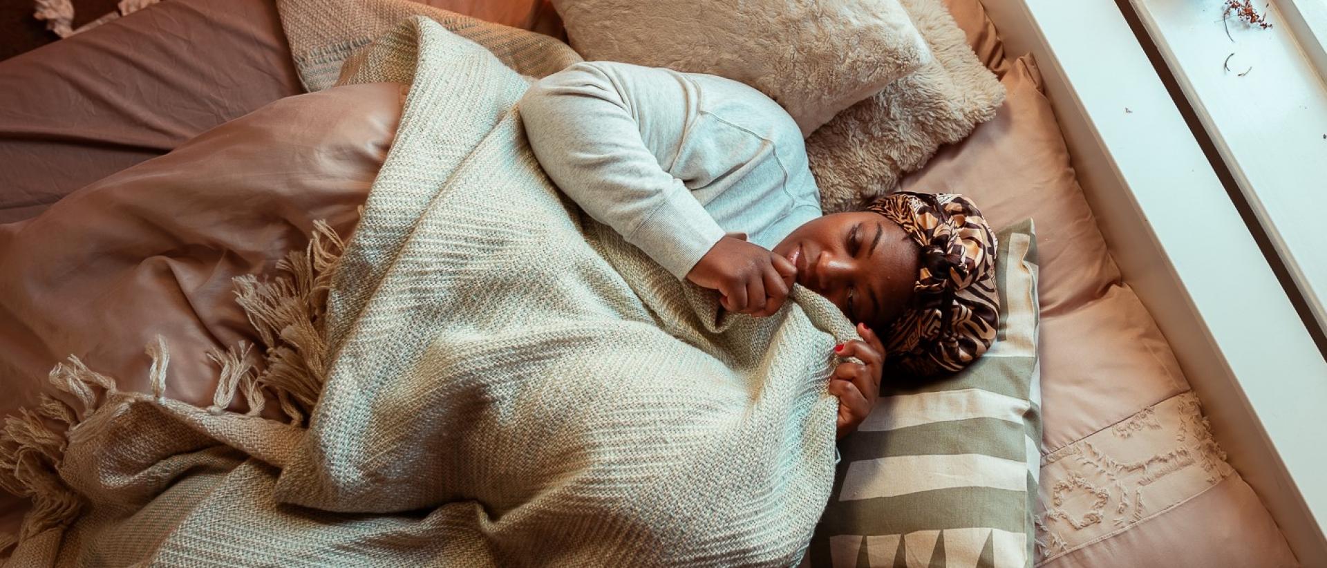 a woman lying in bed cuddling a pillow