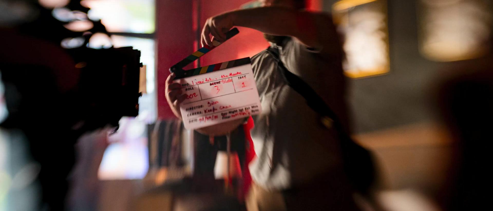 a person standing in front of a camera with a clapperboard