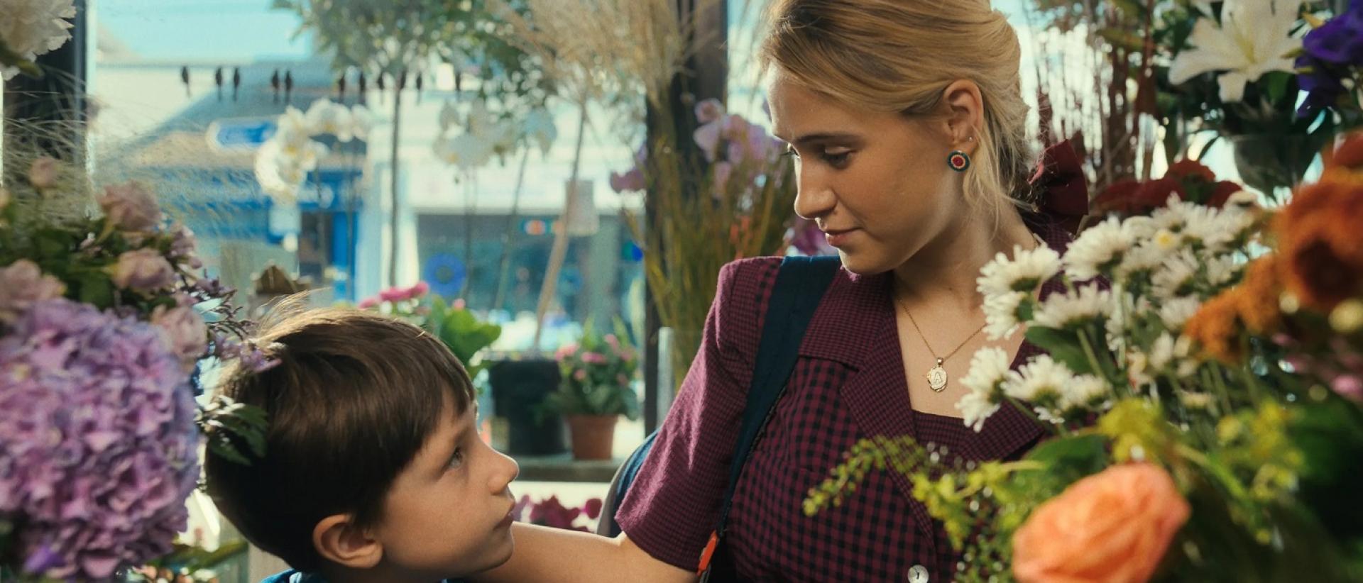 still from learning to breathe under water featuring a young boy and a woman standing in a florist