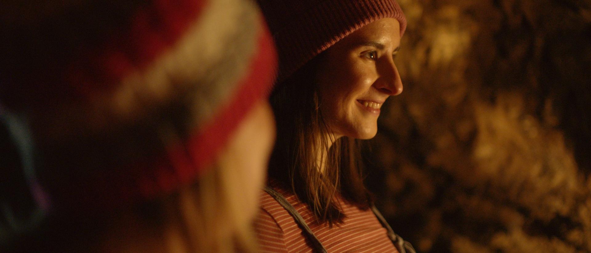 still from jelly featuring two women wearing woolly hats standing in a cave