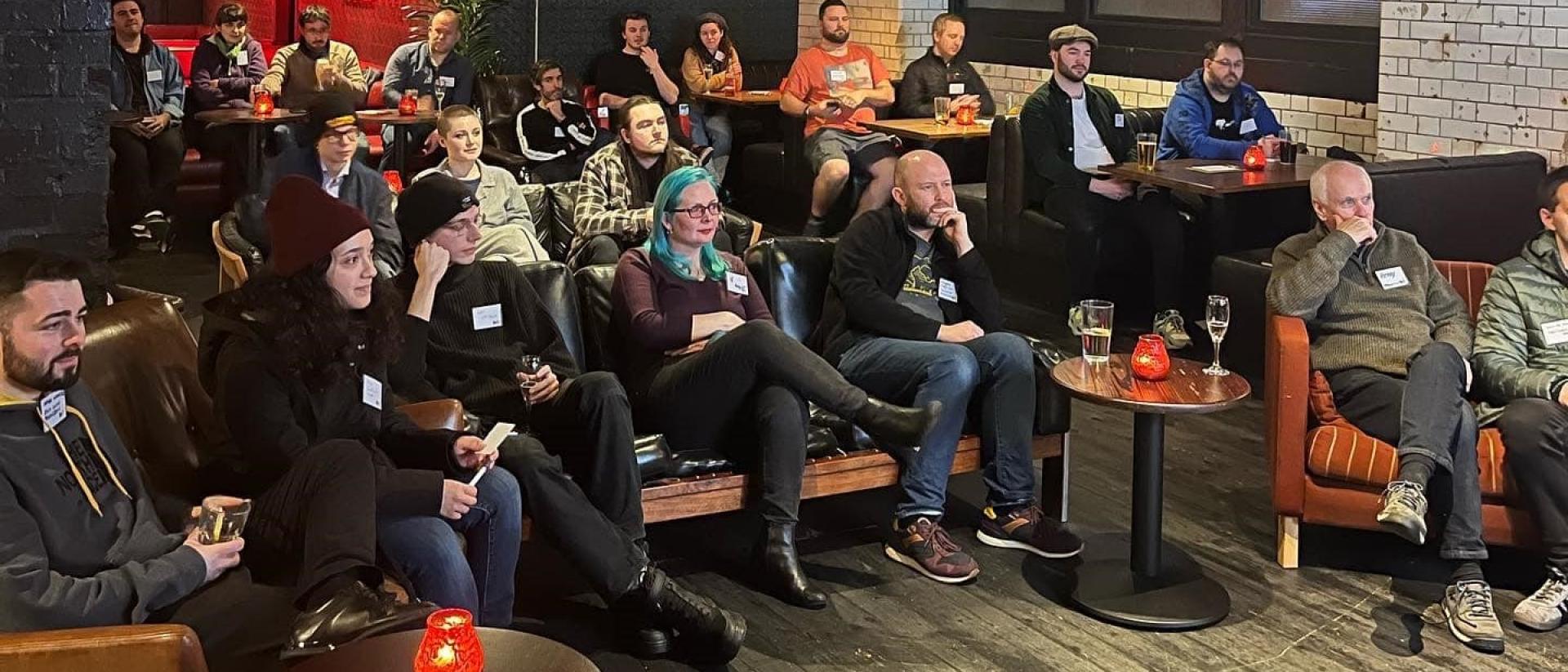a group of people sitting in a room watching a panel discussion