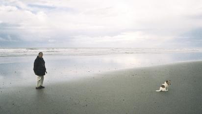 A woman and her dog on an empty beach