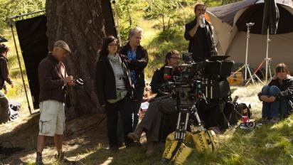 a photo of a film crew shooting in a grassy and wooded area