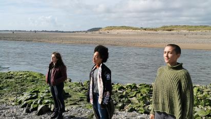 a photo of three people standing next to the sea as part of a dance performance