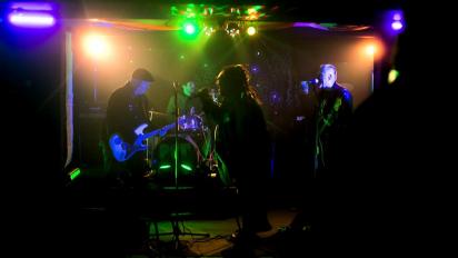 Still from King of the Pit featuring a four-piece rock band playing a gig.