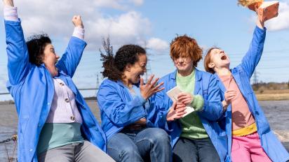 still from chuck chuck baby featuring four people sitting on a wall and celebrating