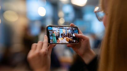 photo of a person filming an event on their phone