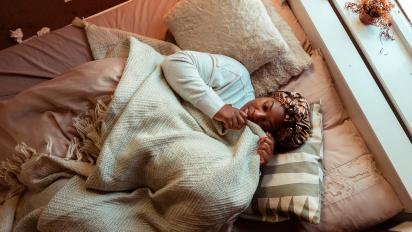 a woman lying in bed cuddling a pillow