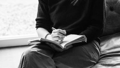 black and white photo of someone writing in a notebook