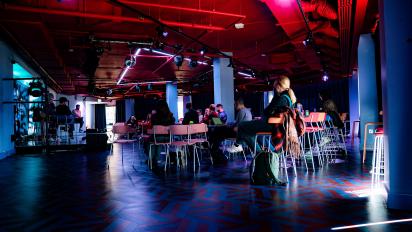 Photo of a cabaret style room with people sitting and watching a panel discussion taking place on stage.