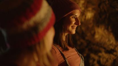 still from jelly featuring two women wearing woolly hats standing in a cave
